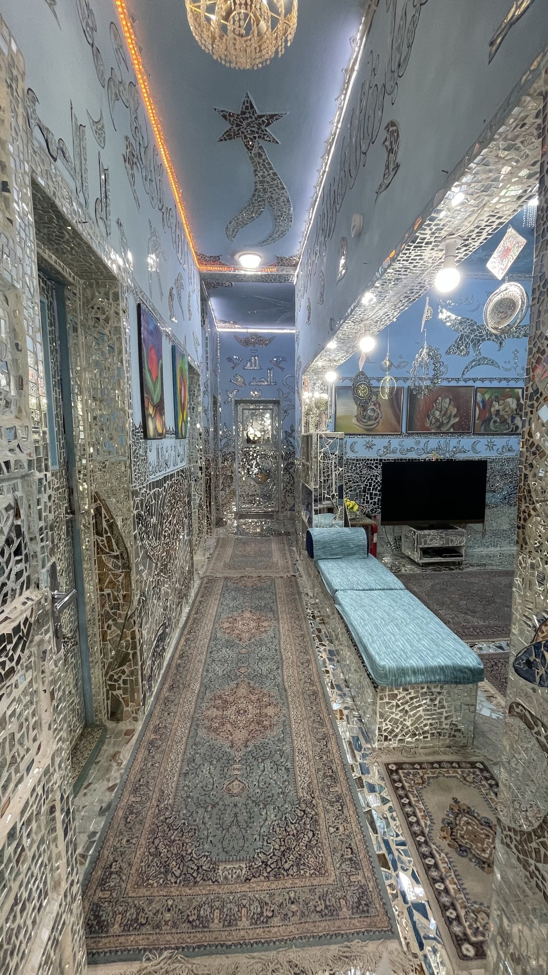 A mirrored corridor lit by a chandelier