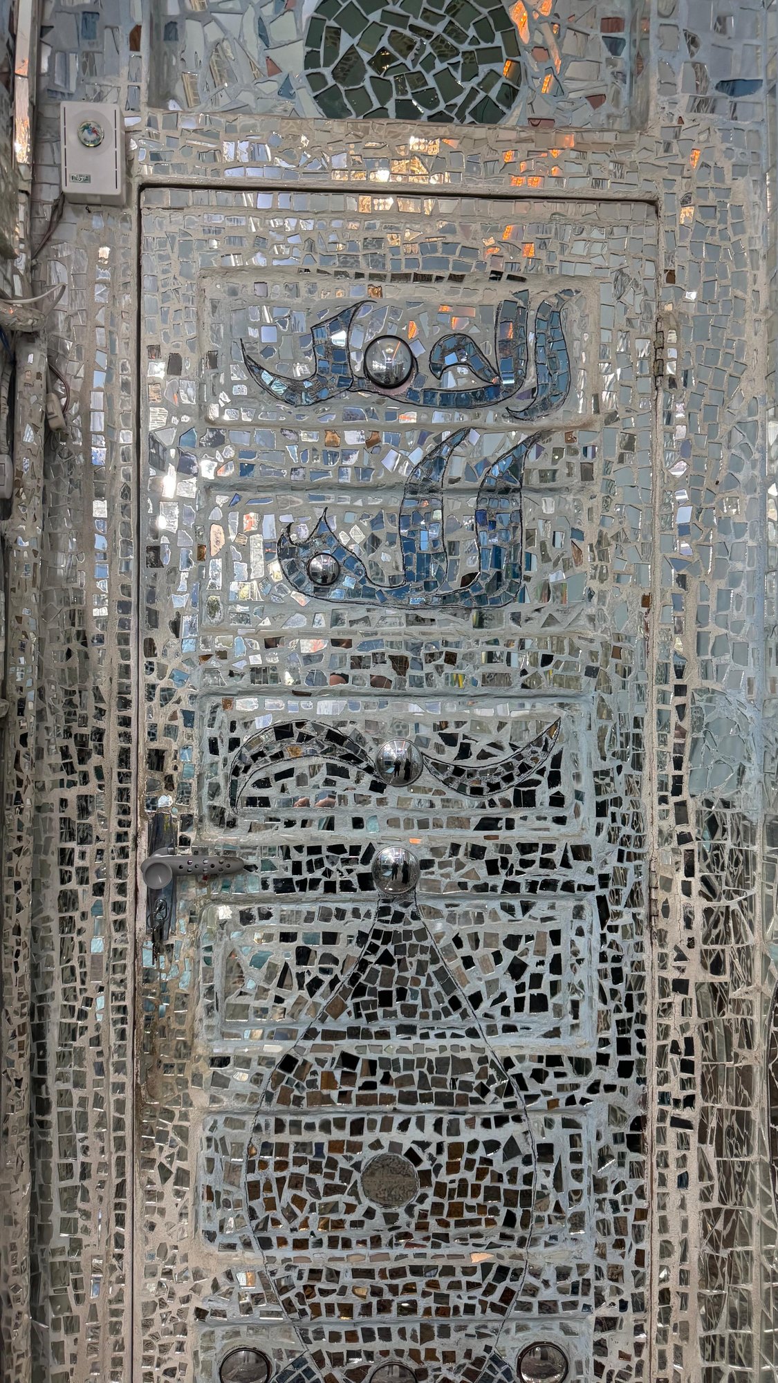 A door surfaced entirely in mirror mosaic and calligraphy