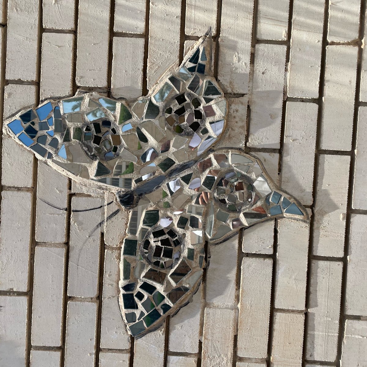 A close view of one mirror-mosaic butterfly on the brick wall